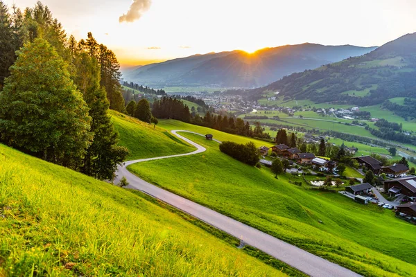 Coucher de soleil romantique dans les montagnes. Route sinueuse rurale alpine, prairies verdoyantes et hauts sommets des Alpes autrichiennes. Pinzgau, Autriche — Photo