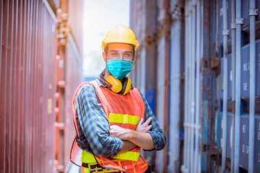 Portre işçisi inceleme altında ve fabrikadaki kirliliği ve virüsü korumak için güvenlik maskesi takarak liman istasyonunda radyo iletişimiyle üretim sürecini kontrol ediyor..
