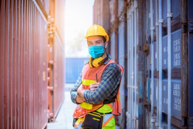 Portre işçisi inceleme altında ve fabrikadaki kirliliği ve virüsü korumak için güvenlik maskesi takarak liman istasyonunda radyo iletişimiyle üretim sürecini kontrol ediyor..