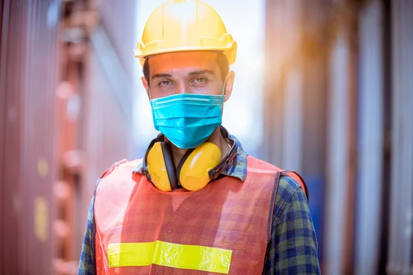 Portre işçisi inceleme altında ve fabrikadaki kirliliği ve virüsü korumak için güvenlik maskesi takarak liman istasyonunda radyo iletişimiyle üretim sürecini kontrol ediyor..