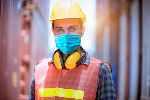 Portrait man dock worker under inspection and checking production process on dock station with radio communication by wearing safety mask to protect for pollution and virus in factory.