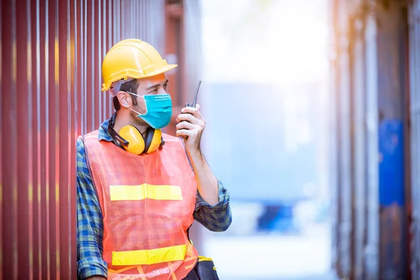 Portrait man dock worker under inspection and checking production process on dock station with radio communication by wearing safety mask to protect for pollution and virus in factory.