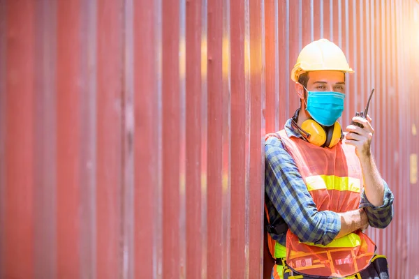工場の汚染やウイルスを保護するために安全マスクを着用することにより 無線通信でドックステーション上の検査や生産プロセスをチェック中の肖像男性ドック労働者 — ストック写真