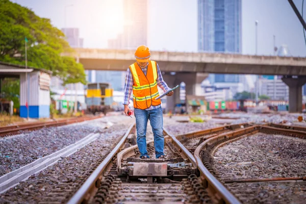 Engineer under inspection and checking construction process railway switch and checking work on railroad station .Engineer wearing safety uniform and safety helmet in work.