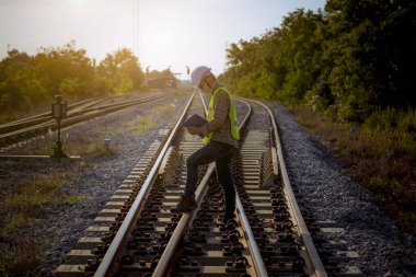 Mühendis teftiş altında ve inşaat istasyonunu kontrol ediyor. Güvenlik üniforması ve güvenlik kaskı takan mühendis, virüsten korunmak için maske takıyor.. 