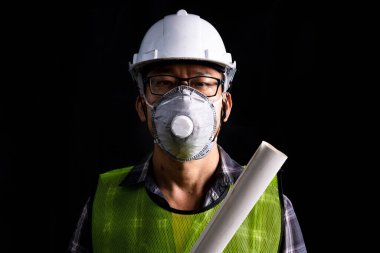 Mühendis teftiş altında ve inşaat istasyonunu kontrol ediyor. Güvenlik üniforması ve güvenlik kaskı takan mühendis, virüsten korunmak için maske takıyor.. 