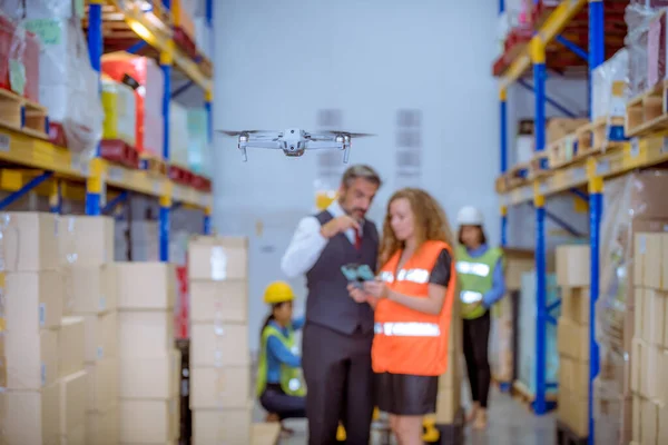Industry engineer and worker under operation control drone flying work in factory and see detail industry warehouse.