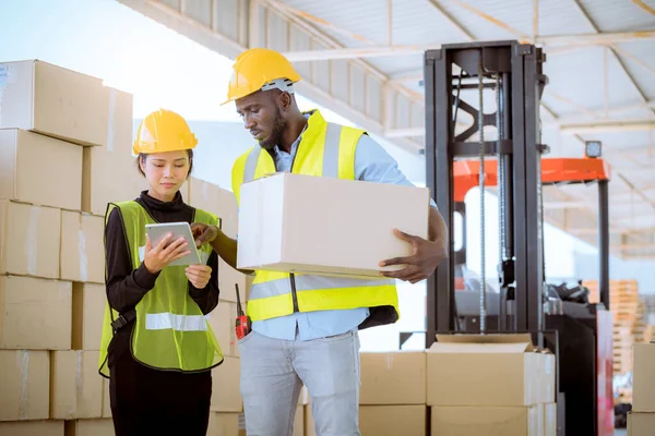 Industry workers helping to move produce boxes for folklife truck to keep on factory warehouse ,they look  produce detail on tablet with factory background