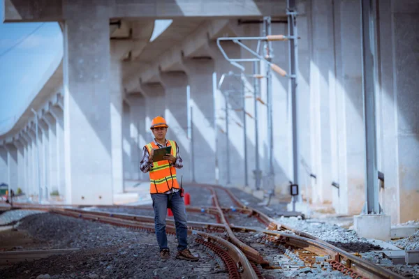 Engineer under inspection and checking construction process railway switch and checking work on railroad station .Engineer wearing safety uniform and safety helmet in work.