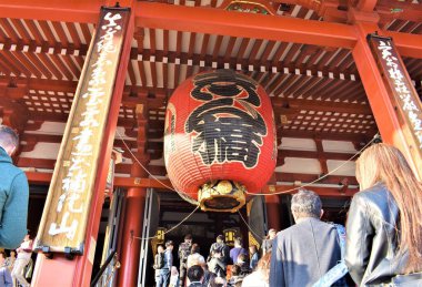 Devasa bir kırmızı fener kendini adamışlarla dolu bir Çin tapınağının girişini süslüyor.