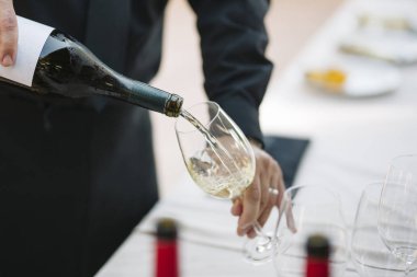 Bir kadeh beyaz şarap servis eden tanınmayan garson