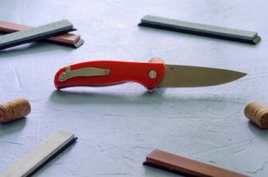 Taşlama taşları ile dokulu mavi arka plan üzerinde parlak katlanır bıçak, çelik sınıf D2