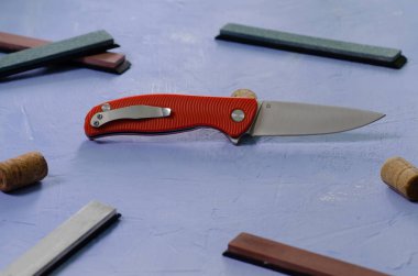 Taşlama taşları ile dokulu mavi arka plan üzerinde parlak katlanır bıçak, çelik sınıf D2