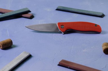 Taşlama taşları ile dokulu mavi arka plan üzerinde parlak katlanır bıçak, çelik sınıf D2