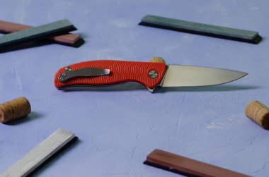 Taşlama taşları ile dokulu mavi arka plan üzerinde parlak katlanır bıçak, hiçbir logo