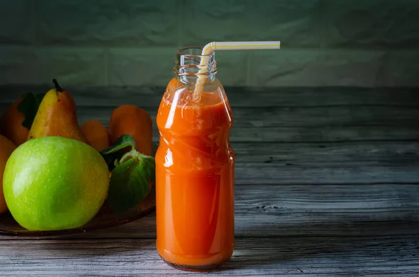 Fresh juice from orange green apple with pears and carrots in a bottle with a straw front view on wooden background — Stock Photo, Image