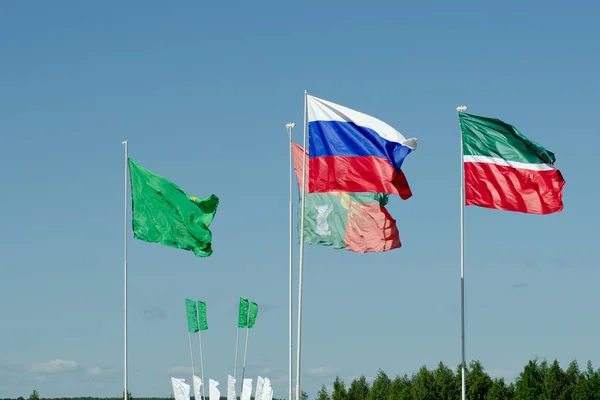 The national flag of Russia and the flag of the Republic of Tatarstan against the blue sky are developing in the wind