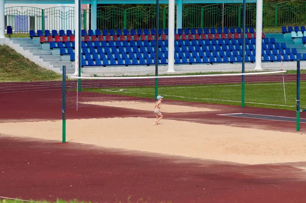 Chłopiec gra na sztucznym boiskiem do siatkówki plażowej na stadionie na świeżym powietrzu — Zdjęcie stockowe