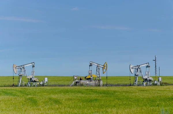 Rocking chair for oil production in a green field on a sunny day against a blue sky background