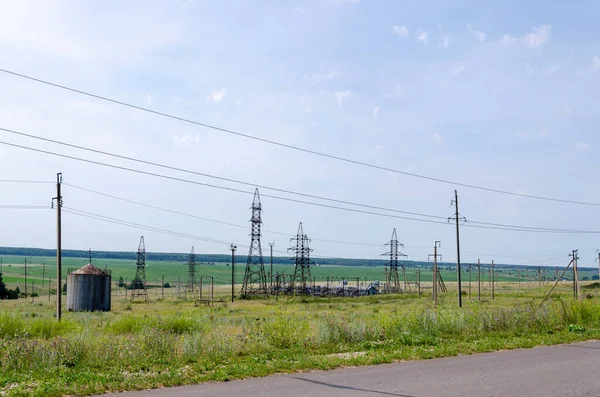 Torres de alto voltaje con cables en un campo verde en un día soleado de verano — Foto de Stock