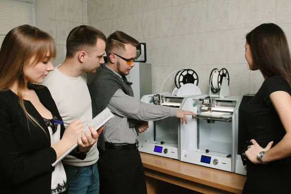 The group of young students work using a 3D printer