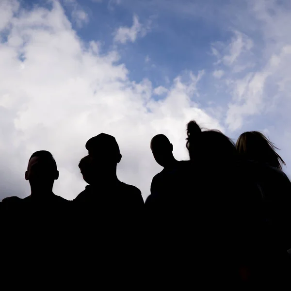 Uma silhueta de um grupo de pessoas com no fundo — Fotografia de Stock