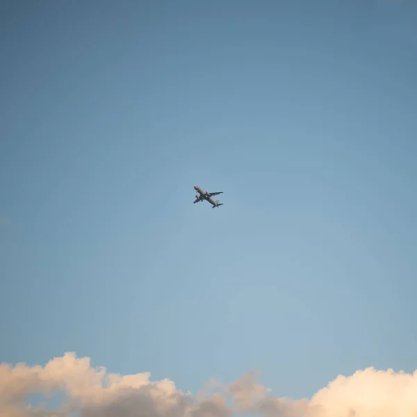 Fliegendes Flugzeug am Himmel mit Wolken bei Sonnenuntergang als Hintergrund — Stockfoto