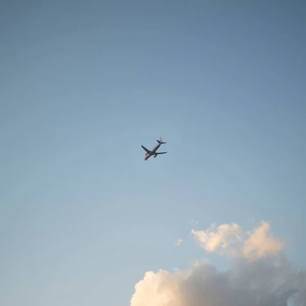 Fliegendes Flugzeug am Himmel mit Wolken bei Sonnenuntergang als Hintergrund — Stockfoto