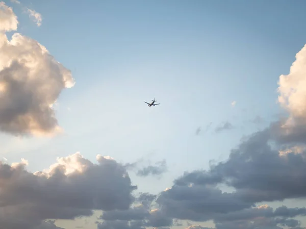 Bir arka plan olarak gün batımında bulutlar ile gökyüzünde Uçan uçak — Stok fotoğraf