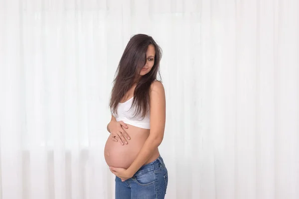 Zwangere Vrouw Jeans Witte Top Houdt Handen Buik Een Witte — Stockfoto