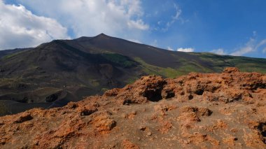 Büyük, pas rengi kayalar, kül konisi ve volkanik kraterle engebeli volkanik manzara. Volkanik bölgenin güçlü güzelliği, Etna Dağı 'nın eşsiz çevresi. Seyahat, doğa, jeoloji.