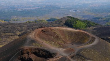 Etna Dağı volkanik kraterinin canlı kırmızı ve siyah lav kayalarıyla hava görüntüsü. Siyah volkanik kül, kırmızı renkli yamaçlar ve yeşil bitki örtüsü manzarası. Doğa, jeoloji ve Etna Dağı ile ilgili macera.