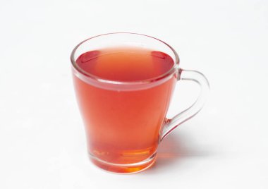 Bej arka planda, bardakta kırmızı meyve suyu.