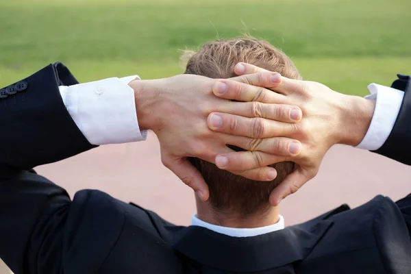 Genç İşadamı, öğle yemeği frenleri kafasının arkasındayken parkta dinleniyor.