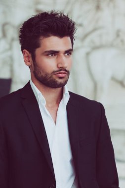 Güzel saçlı ve sakallı yakışıklı ve genç bir adam. Çekici bir adamın portresi. Beyaz gömlek ve ceket..