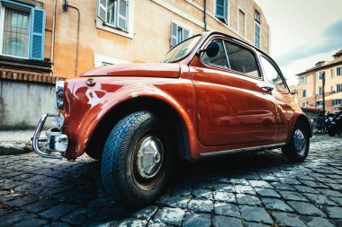 Eski İtalyan arabası Fiat 500 Cinquecento İtalya 'nın tarihi merkezine park edilmiştir. Turuncu renk, kaldırım taşlarıyla döşenmiş..