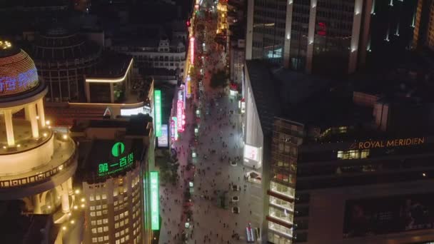 Gente en Nanjing Road por la noche. Calle peatonal en el distrito de Huangpu. Ciudad de Shanghai, China. Vista aérea. Drone vuela hacia abajo, cámara se inclina hacia arriba, revelar disparo — Vídeo de stock