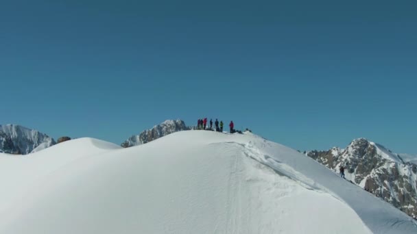 Les gens au sommet de la montagne enneigée en journée ensoleillée. Vue Aérienne — Video