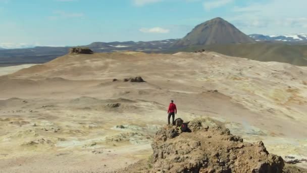 Человек-путешественник стоит на вершине горы. Исландия. Вид с воздуха — стоковое видео