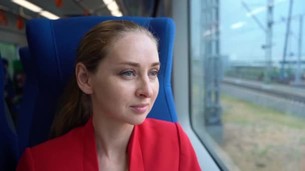 Junge Frau im roten Blazer im fahrenden Zug schaut in Fenster — Stockvideo