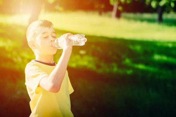 Malý chlapec pitné vody z plastových lahví — Stock fotografie