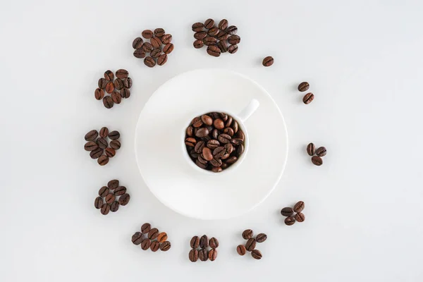 Taza de café en platillo y granos de café en forma de reloj — Foto de Stock
