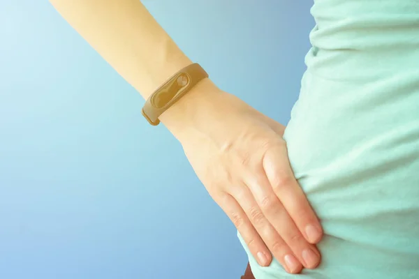 Woman with fitness tracker on hand on blue background — Stock Photo, Image