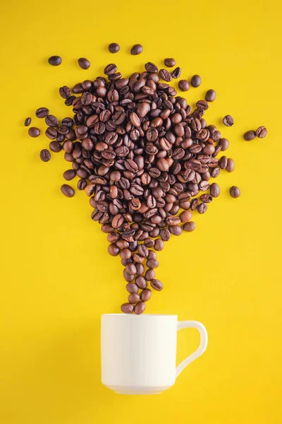 Creative food photo. Coffee beans exploding with fireworks from a cup on a yellow background