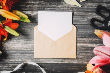 Zambak çiçekler koyu ahşap arka plan üzerinde olan mockup beyaz kart ve zanaat zarf