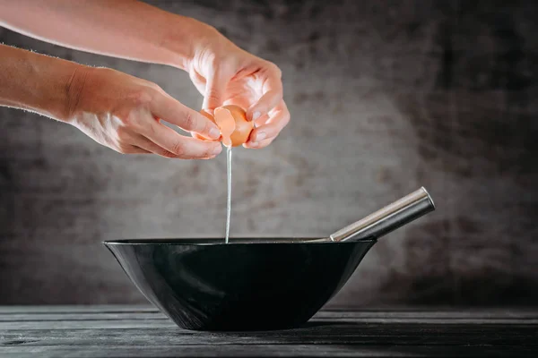 Жінка розтріскує яйце в миску для приготування торта в кухонній кімнаті — стокове фото