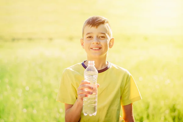 Jonge jongen houdt waterfles drankje en glimlach — Stockfoto
