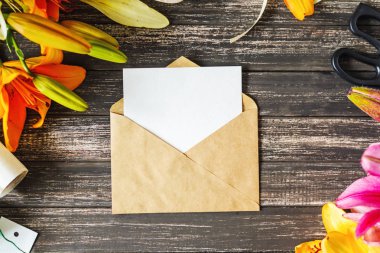 Zanaat zarf ve dekorasyon ahşap masaya çiçek ile beyaz boş sayfa. Tebrik kartı için düzen. Üstten görünüm kadar alay