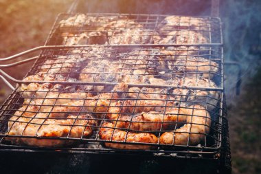 sosis, tavuk ızgarada pişirilir. Dumanlı Barbekü pişirme işlemi