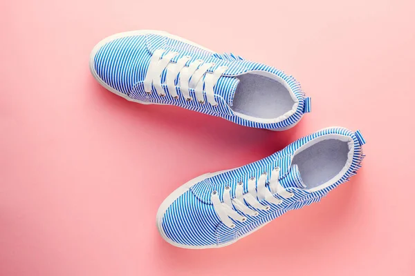 Mavi çizgili erkek spor ayakkabı pastel pembe bir arka plan üzerinde. Düz yatıyordu, en iyi görünümü